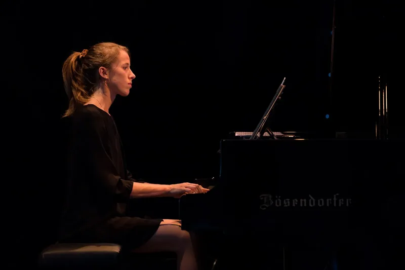 Alexandra Tchernakova playing a Bösendorfer grand piano on a dark stage
