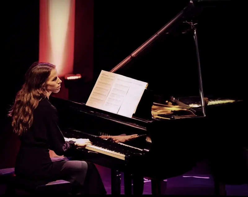 Alexandra Tchernakova playing on a concert stage in red and purple light