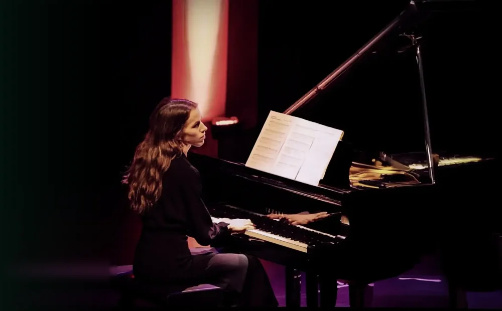 Alexandra Tchernakova playing on a concert stage in red and purple light